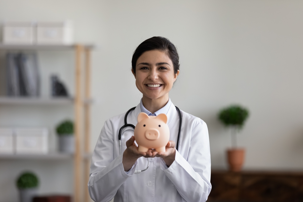 Medical student holding a piggy bank